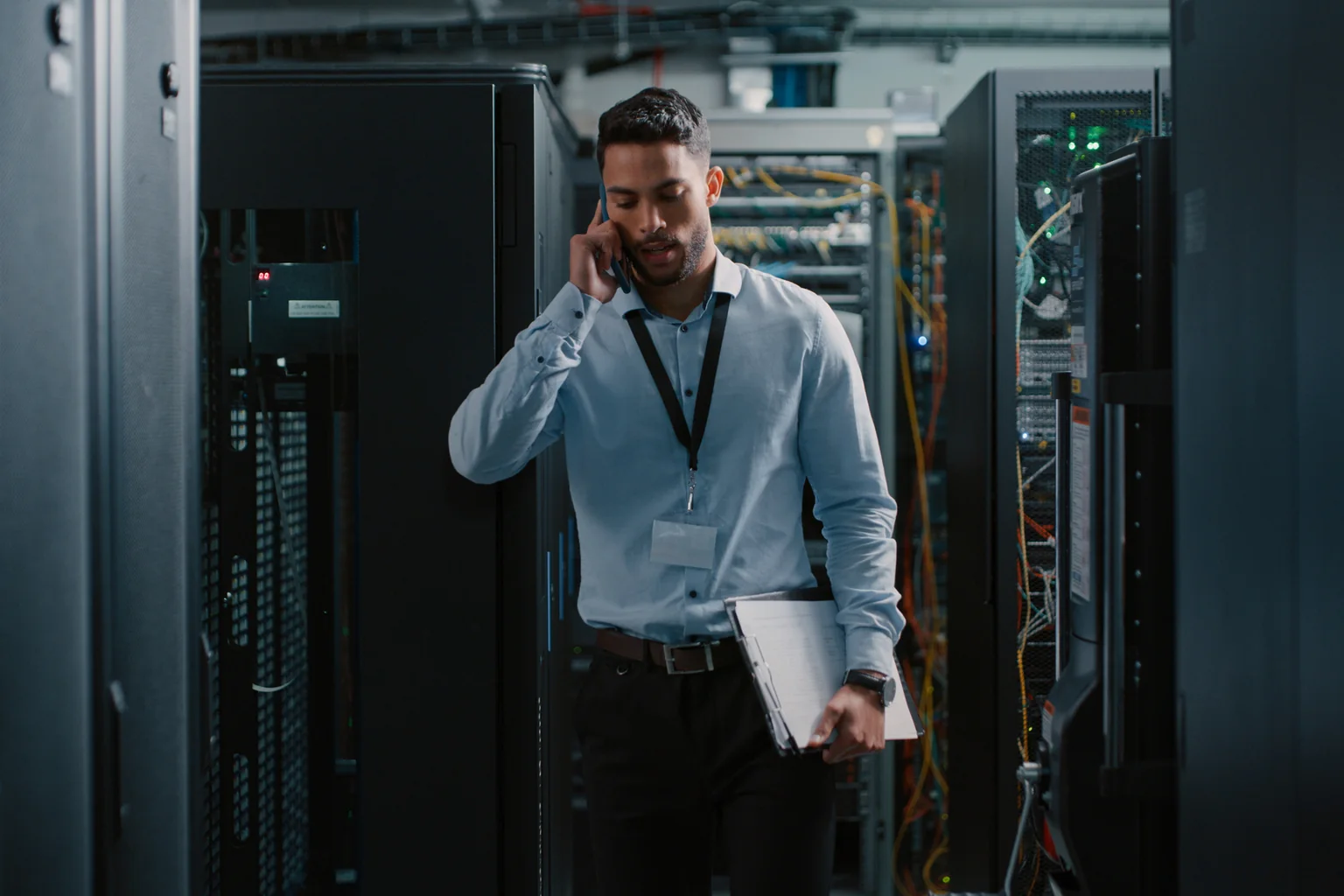 A data center engineer taking a call while walking a server aisle.