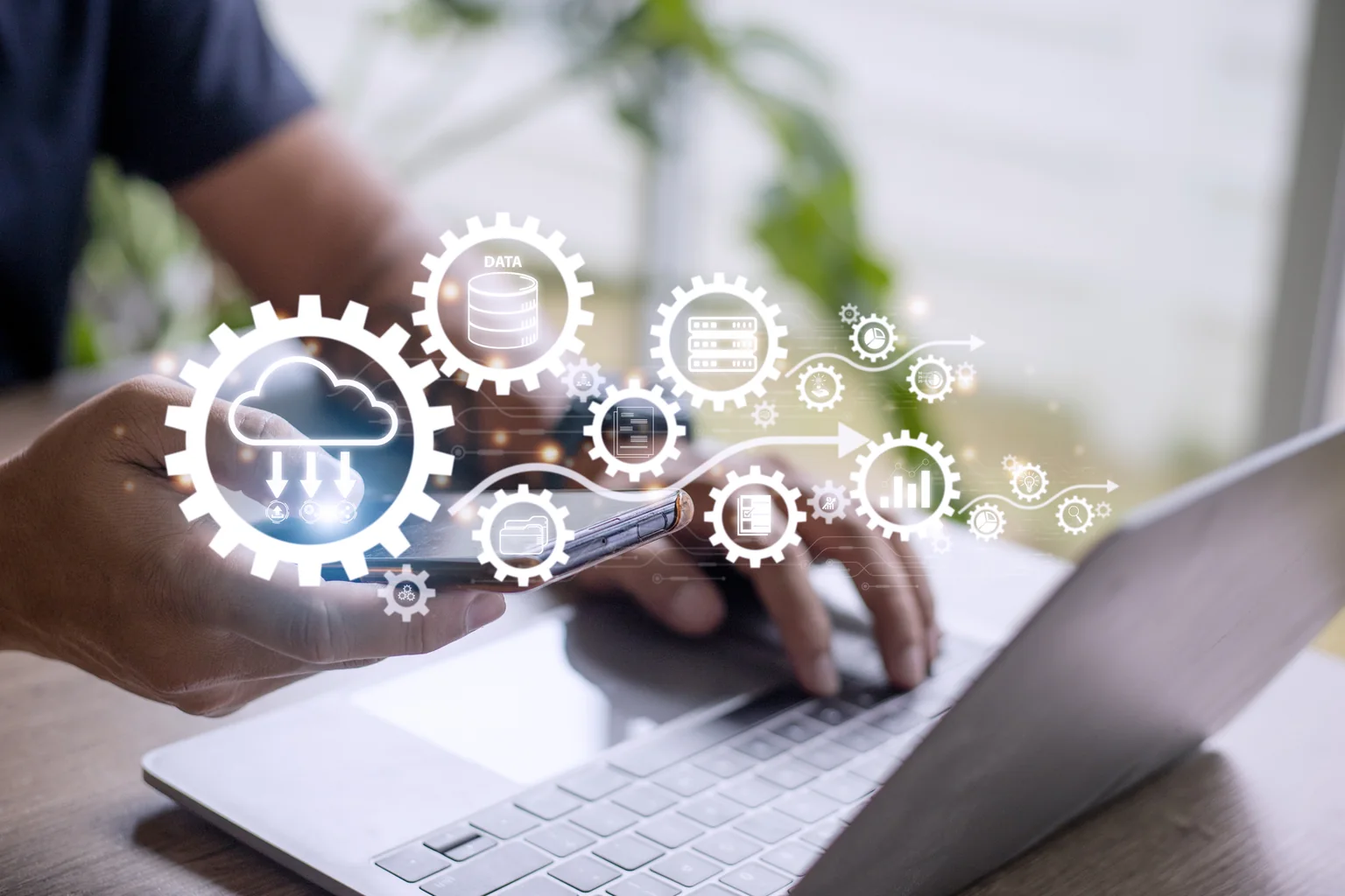 Cloud and automation icons over a laptop and phone on a desk.