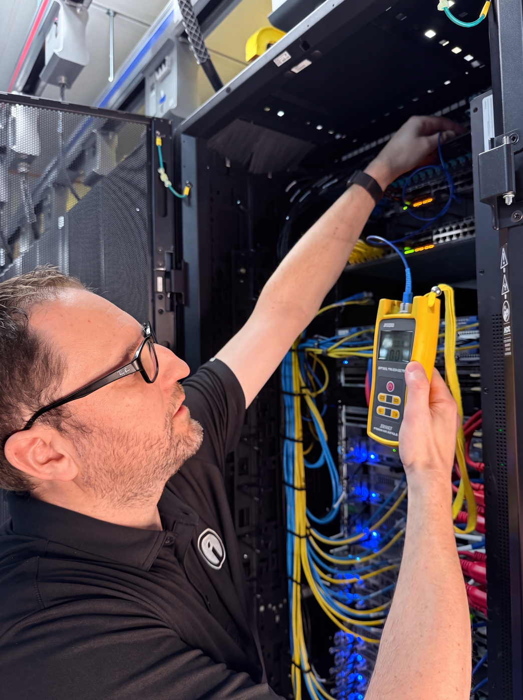 An Opus Interactive engineer testing a fibre connection with an optical power meter at an open rack