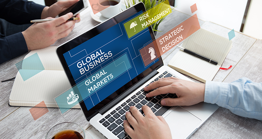 An Opus Interactive blog post image of a man working on a laptop, the laptop screen is labeled, "Global business, global markets, risk management, and strategic decision".