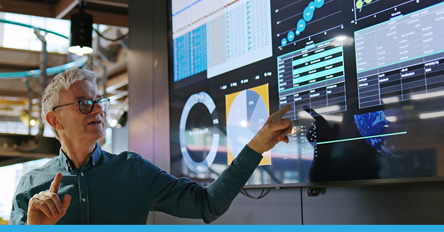 Blog post image of a man presenting data on a tv screen, presumably in a meeting.