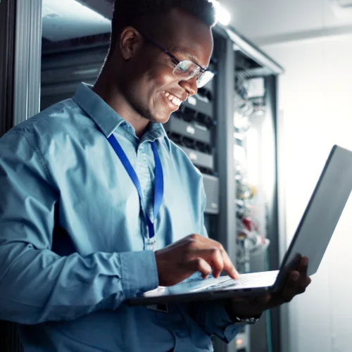 Man in a server room typing on laptop with Opus Interactives secure cloud technology.